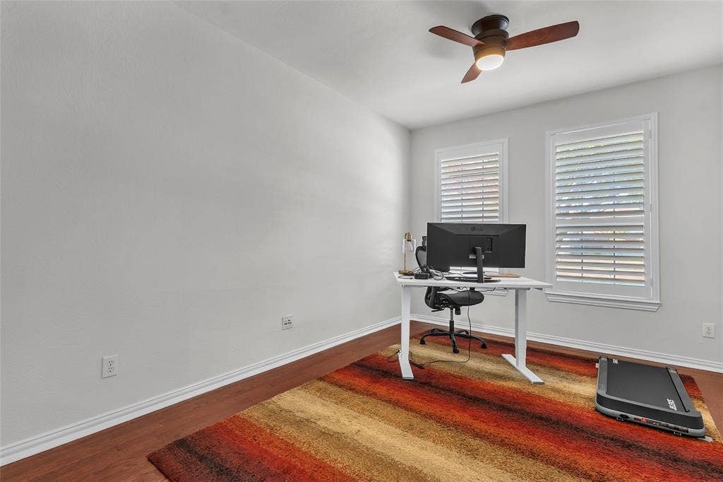 Bedroom with engineered hardwood floors, ceiling fan, and plantation shutters — 5804 Lafayette Dr, Frisco