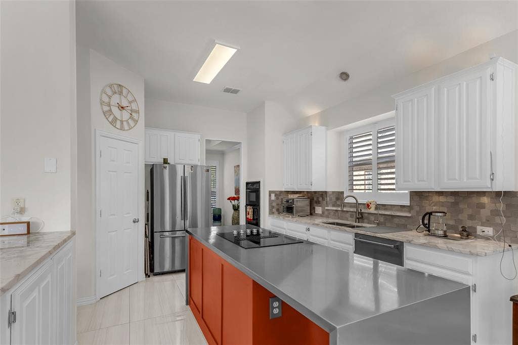 Kitchen with waterfall island, cooktop, double wall oven, and pantry — 5804 Lafayette Dr, Frisco