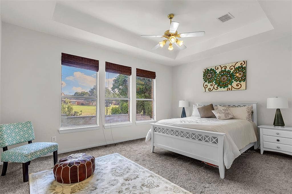 Primary bedroom with three windows overlooking golf course greenery — 5804 Lafayette Dr, Frisco