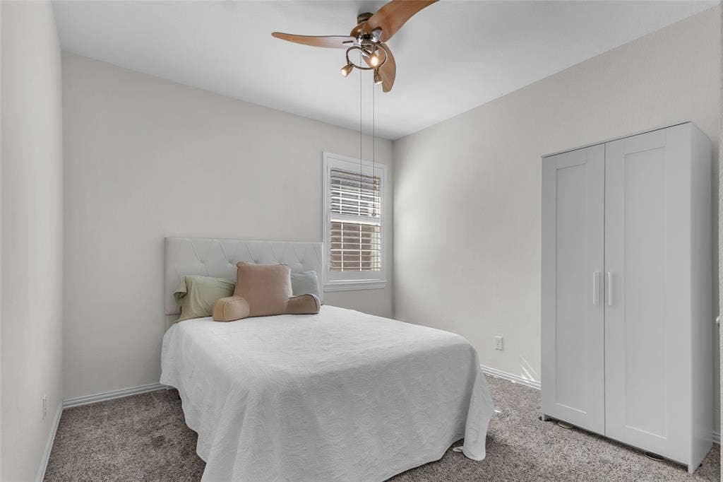Secondary bedroom with carpet, ceiling fan, and shuttered window — 5804 Lafayette Dr, Frisco