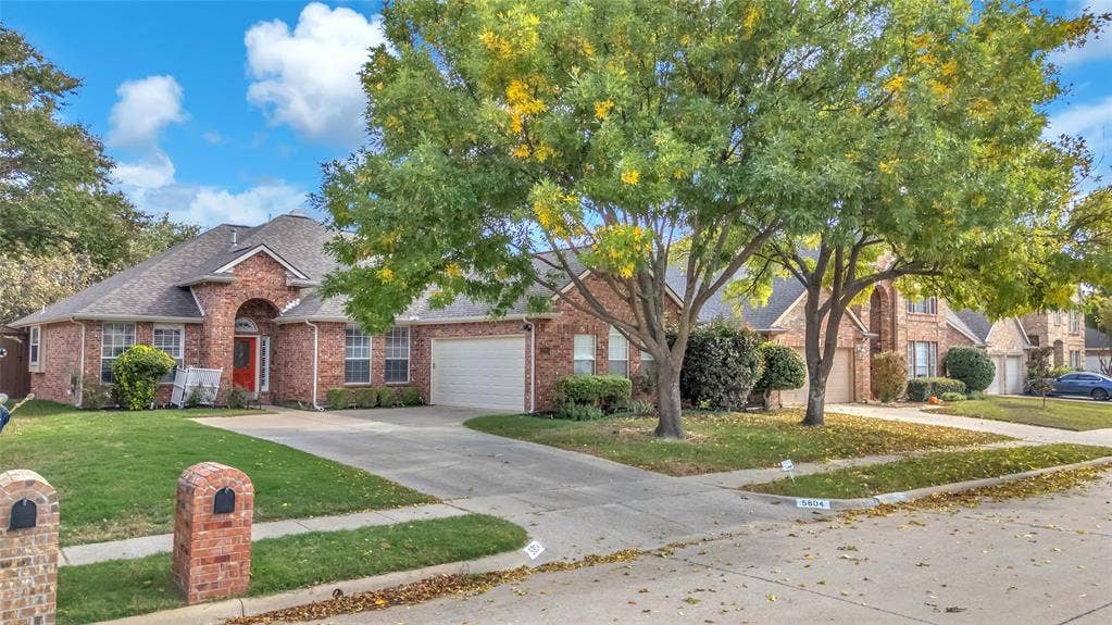 Brick front elevation with arched entry, red door, and 2-car garage — 5804 Lafayette Dr, Frisco
