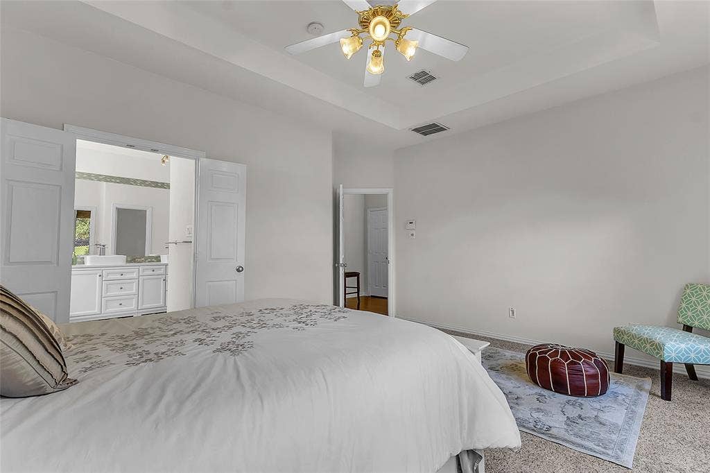 Primary bedroom with tray ceiling, ceiling fan, and bath access — 5804 Lafayette Dr, Frisco