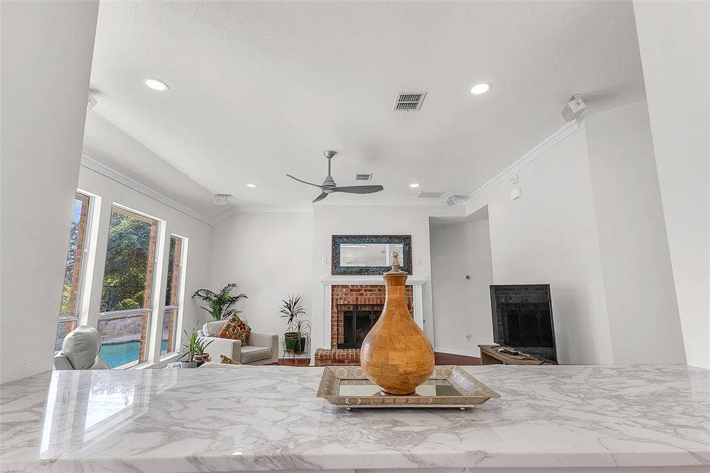 Kitchen view to living room, brick fireplace, and pool through windows — 5804 Lafayette Dr, Frisco