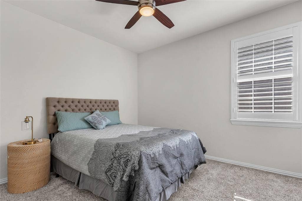 Secondary bedroom with carpet, ceiling fan, and plantation shutters — 5804 Lafayette Dr, Frisco