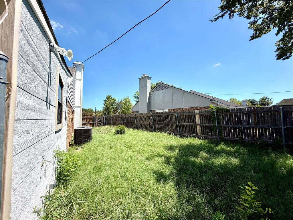 817 Colchester Drive, Mesquite, TX 75149 Expansive backyard featuring a wood fence, mature trees, and an exterior wall with light-colored siding and a brick accent