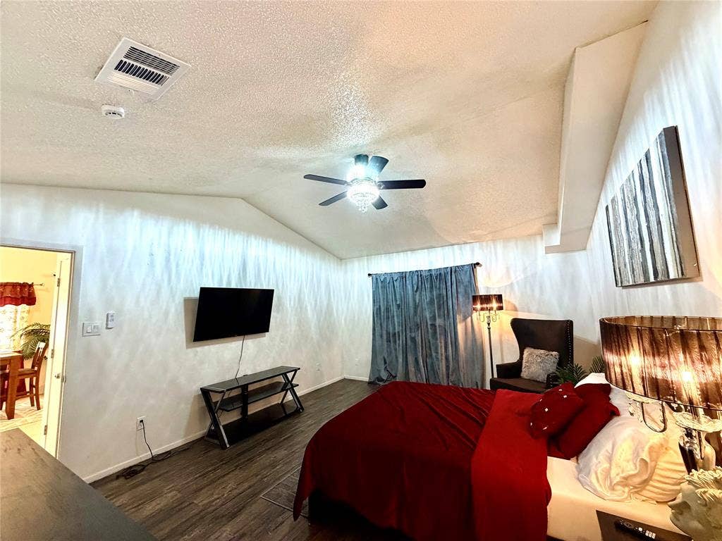 817 Colchester Drive, Mesquite, TX 75149 Vaulted ceiling bedroom featuring wood-finish flooring, a ceiling fan with integrated lighting, and a wall-mounted television