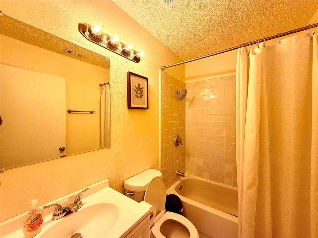 817 Colchester Drive, Mesquite, TX 75149 Bathroom featuring a vanity with an integrated sink, a rectangular mirror, a four-bulb vanity light, and a toilet