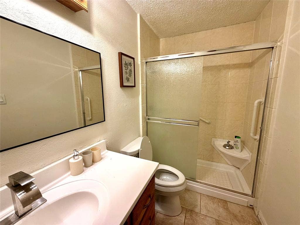 817 Colchester Drive, Mesquite, TX 75149 Bathroom featuring a shower with sliding frosted glass doors, a white shower pan, and a corner shelf