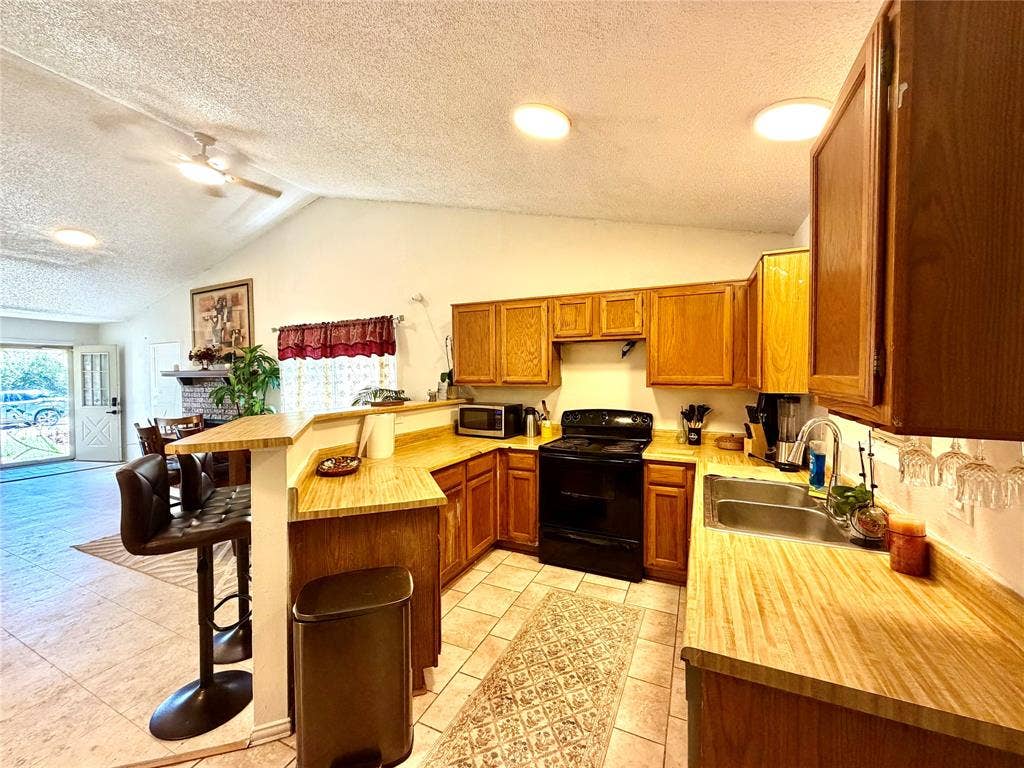 817 Colchester Drive, Mesquite, TX 75149 Open-concept kitchen featuring wood-finish cabinetry, light wood-finish countertops, and a black appliance suite