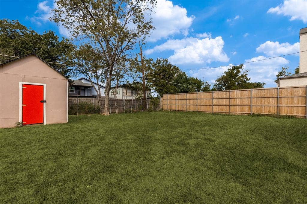 6719 Kenwell Street, Dallas, TX 75209 Expansive backyard featuring a level lawn, full-perimeter wood fencing, and a detached storage structure