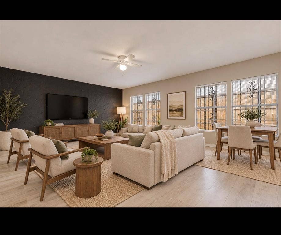6719 Kenwell Street, Dallas, TX 75209 Open-concept living space featuring wood-finish flooring, a charcoal-toned accent wall, and multiple windows with iron security bars, finished with a central ceiling fan *virtually staged*