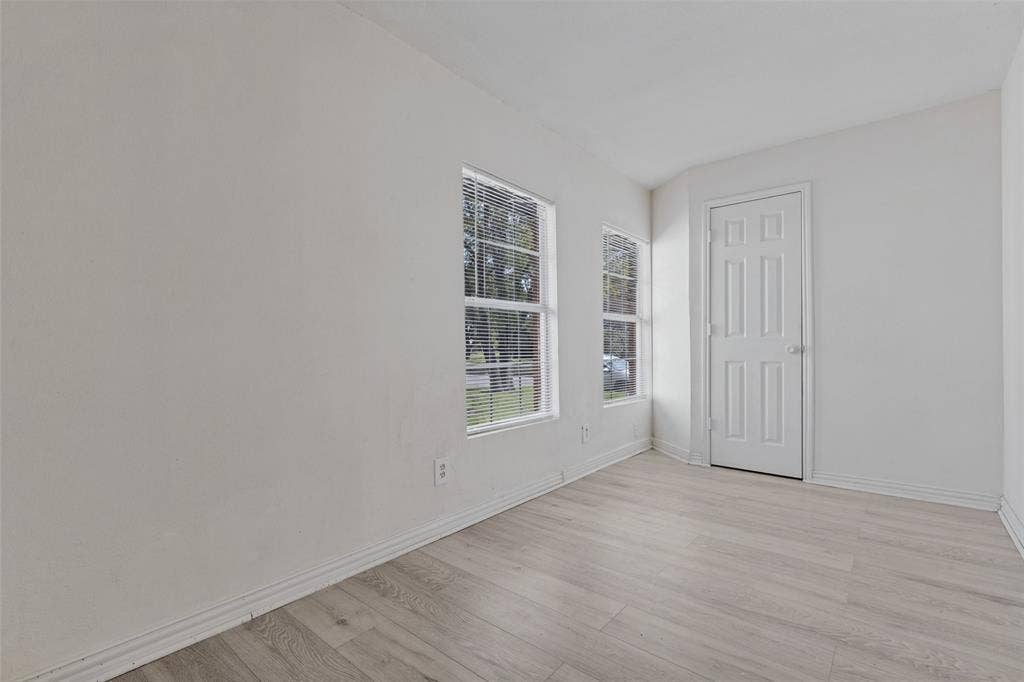 6719 Kenwell Street, Dallas, TX 75209 Neutral-toned interior space featuring light-colored wood-finish flooring, two large windows, and a six-panel door