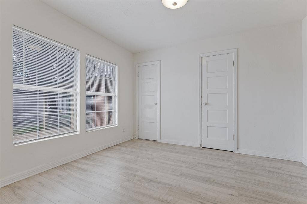 6719 Kenwell Street, Dallas, TX 75209 Neutral-toned interior space featuring wood-finish flooring, two dual-pane windows with integrated blinds, and two classic five-panel interior doors