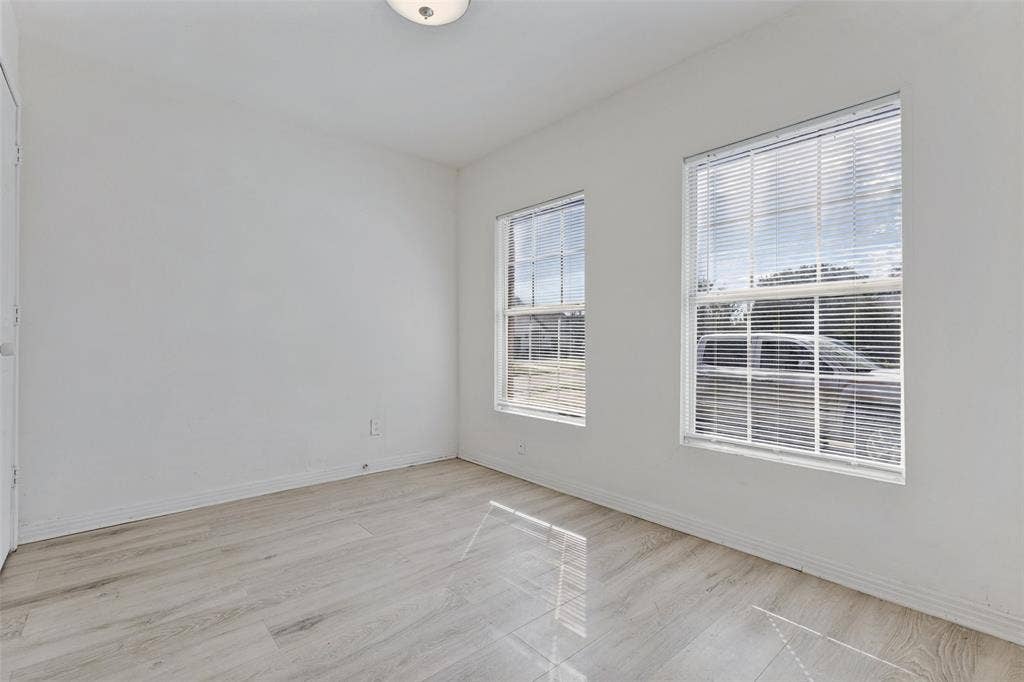 6719 Kenwell Street, Dallas, TX 75209 Room featuring wood-finish flooring, two windows with horizontal blinds, neutral wall paint, and a ceiling-mounted light fixture