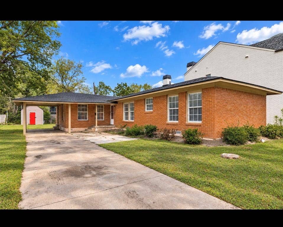 6719 Kenwell Street, Dallas, TX 75209 Single-story brick exterior featuring a covered carport, asphalt shingle roof, multi-pane windows, and a concrete driveway