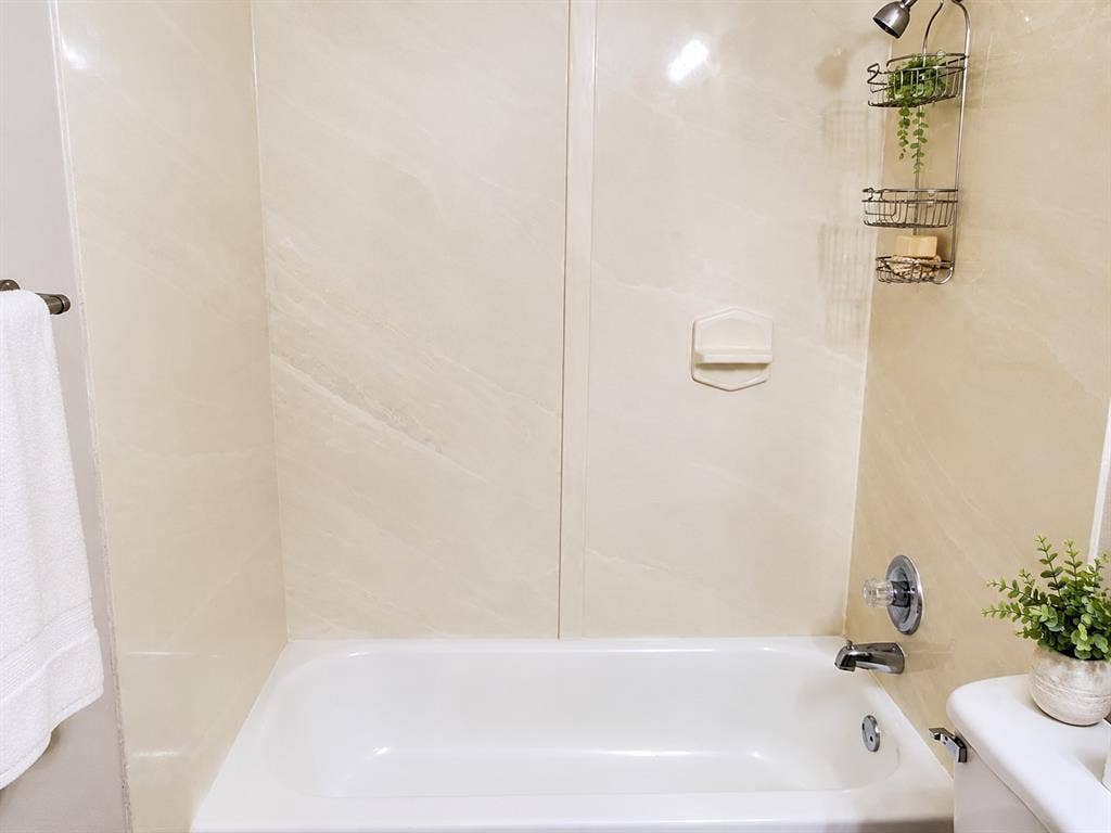 462 Pittman Street, Richardson, TX 75081 Bathtub surround featuring neutral, large-format paneling, integrated soap niche, and chrome-finish hardware