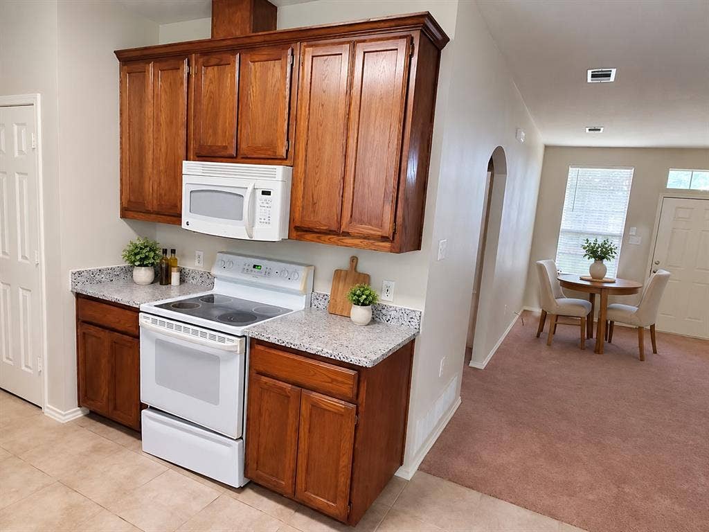 462 Pittman Street, Richardson, TX 75081 Kitchen featuring stained wood cabinetry, speckled stone-finish countertops, and white appliances including a built-in microwave and electric range