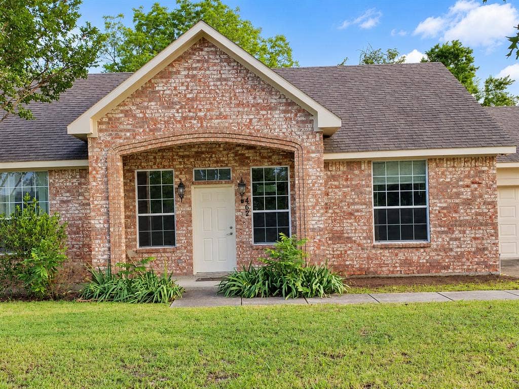 462 Pittman Street, Richardson, TX 75081 Traditional brick exterior featuring a covered entryway with a decorative arched stone header, multi-pane windows, and a shingled roof