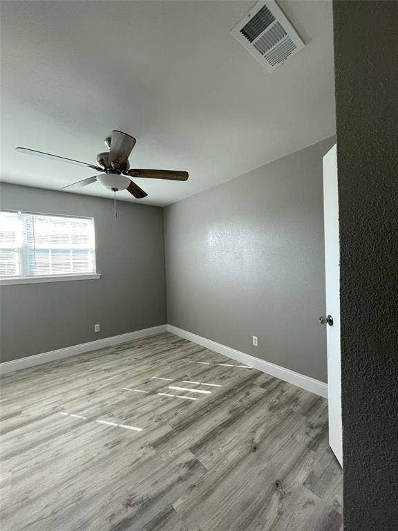 Empty room with light hardwood / wood-style floors and ceiling fan