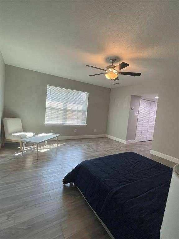 Unfurnished bedroom featuring a textured ceiling, hardwood / wood-style floors, and ceiling fan