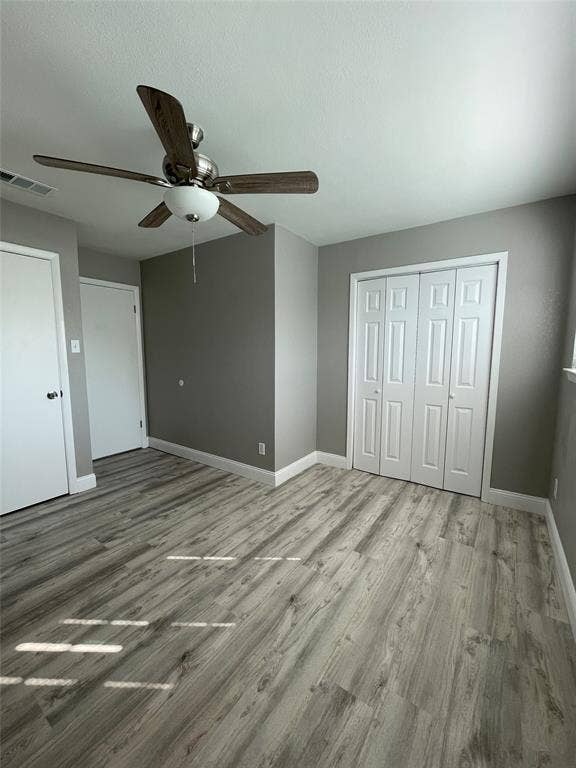 Unfurnished bedroom featuring wood-type flooring, a closet, and ceiling fan