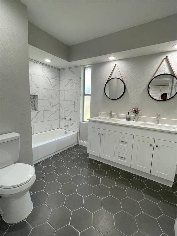 Full bathroom featuring dual vanity, toilet, tiled shower / bath, and tile patterned flooring