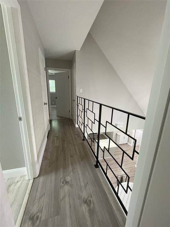 Corridor with lofted ceiling and hardwood / wood-style floors