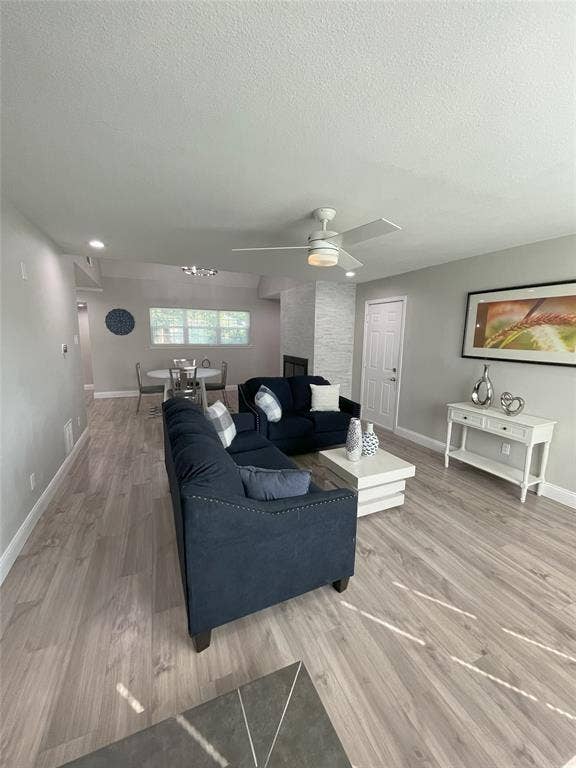 Living room featuring a textured ceiling, hardwood / wood-style floors, and ceiling fan