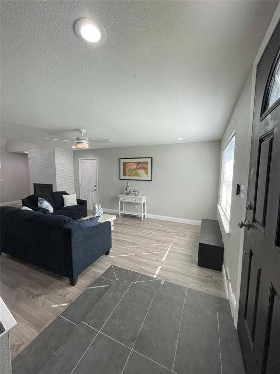 Living room featuring hardwood / wood-style flooring, a textured ceiling, and ceiling fan