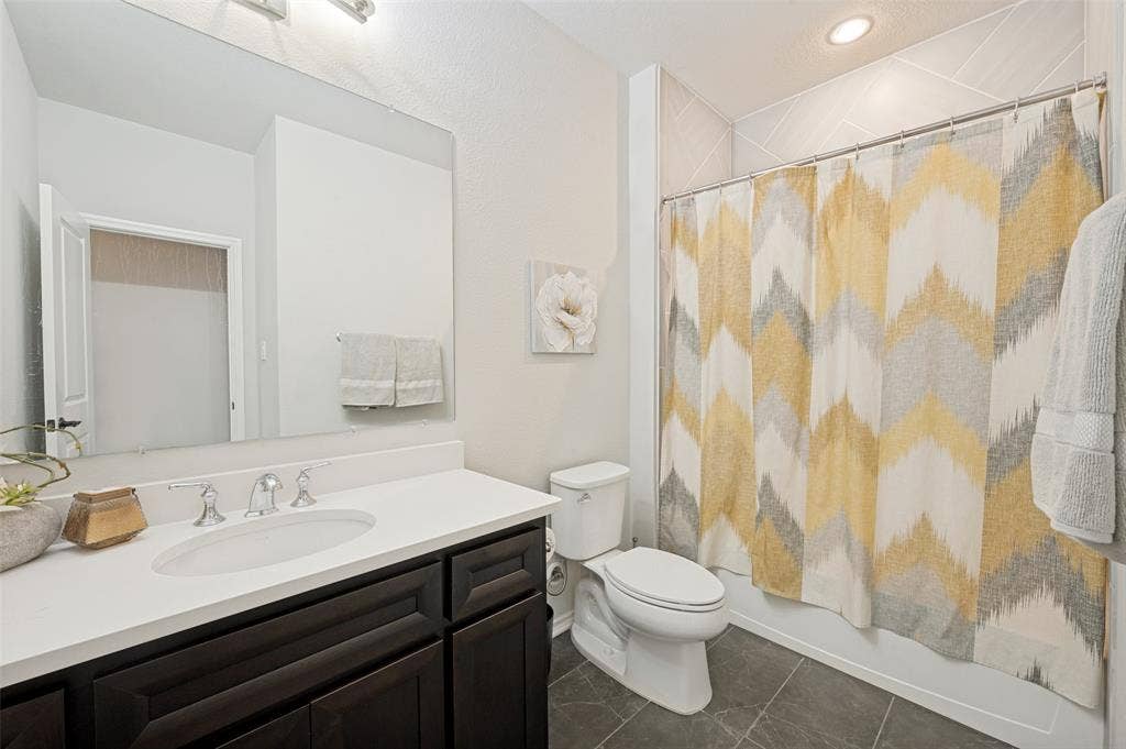 1730 Cottonwood Trail, Prosper, TX 75078 This hallway bathroom features a dark wood vanity and a tub shower.