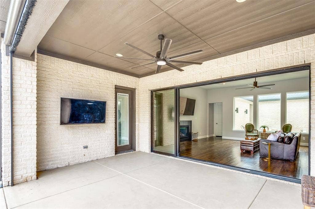 1730 Cottonwood Trail, Prosper, TX 75078 Covered patio with a concrete slab, white brick exterior walls, and a dark ceiling fan