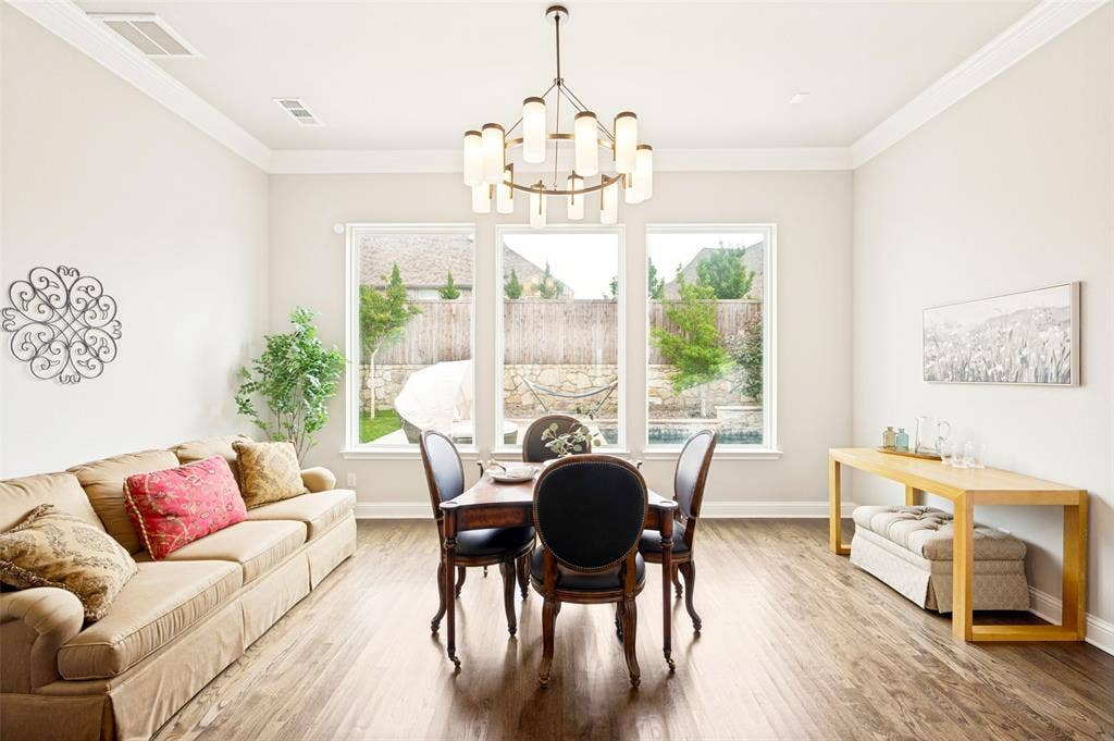 1730 Cottonwood Trail, Prosper, TX 75078 Dining area featuring wood flooring, a contemporary chandelier, and three large windows providing abundant natural light