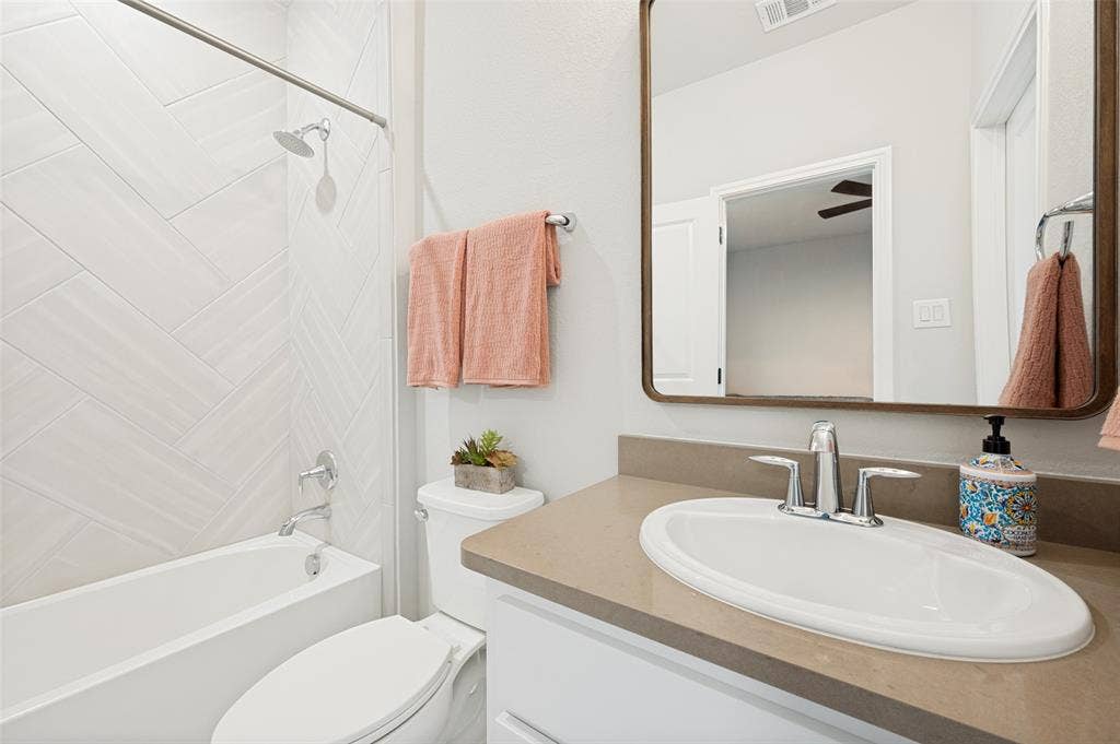 1730 Cottonwood Trail, Prosper, TX 75078 Bathroom featuring a single vanity with an integrated sink, polished chrome faucet, and a framed mirror