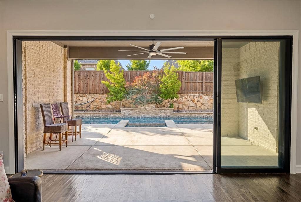 1730 Cottonwood Trail, Prosper, TX 75078 Glass sliding wall leads to expansive outdoor living area featuring a covered patio, swimming pool, and concrete decking.