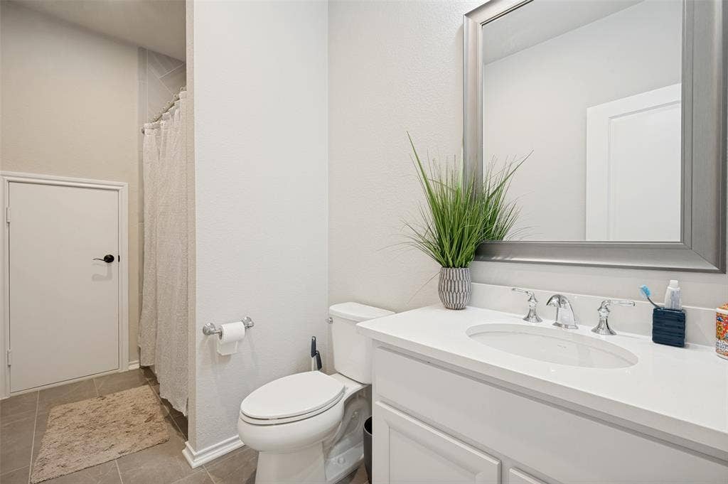 1730 Cottonwood Trail, Prosper, TX 75078 Bathroom featuring a white vanity with an integrated sink, polished chrome faucet, and a framed mirror