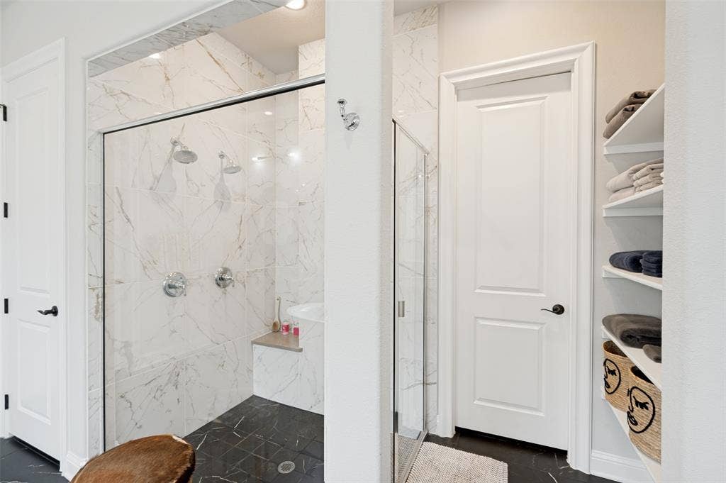1730 Cottonwood Trail, Prosper, TX 75078 Walk-in shower with clear glass enclosure and marbled tile surround. This ensuite also features two walk-in-closets.