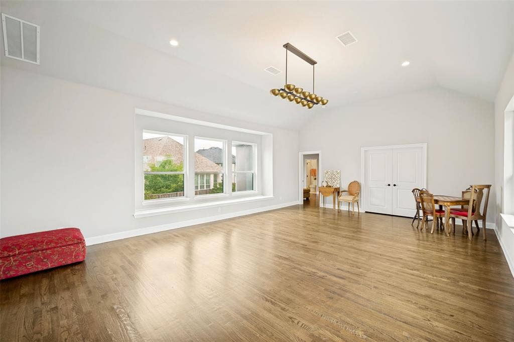 1730 Cottonwood Trail, Prosper, TX 75078 Spacious gameroom featuring vaulted ceilings, wood flooring, a contemporary linear chandelier, recessed lighting, and a multi-pane window with a window ledge.