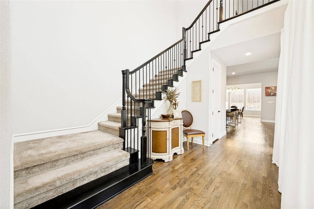 1730 Cottonwood Trail, Prosper, TX 75078 Grand entryway featuring a curved staircase with black newel posts and wrought iron balusters leading to open living area.