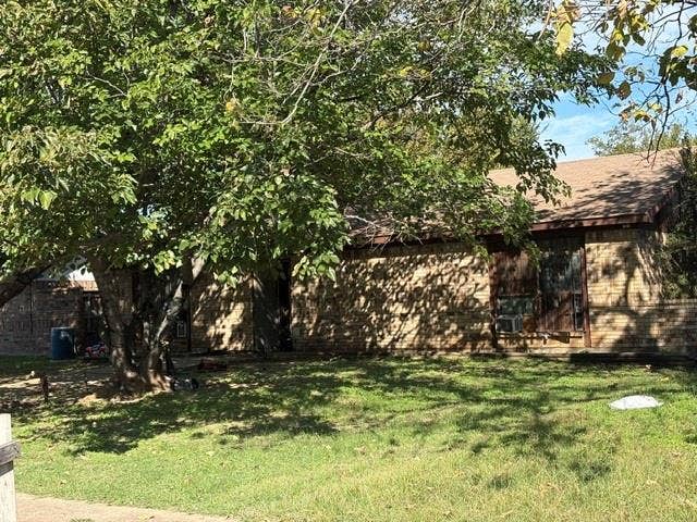 10311 Kinslow Drive, Dallas, TX 75217 Single-story residence featuring a brick facade, asphalt shingle roof, and mature trees on the lot