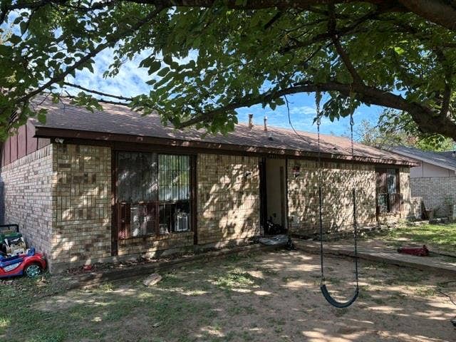 10311 Kinslow Drive, Dallas, TX 75217 Single-story exterior featuring a brick facade, low-pitch shingle roof, and large windows with dark trim