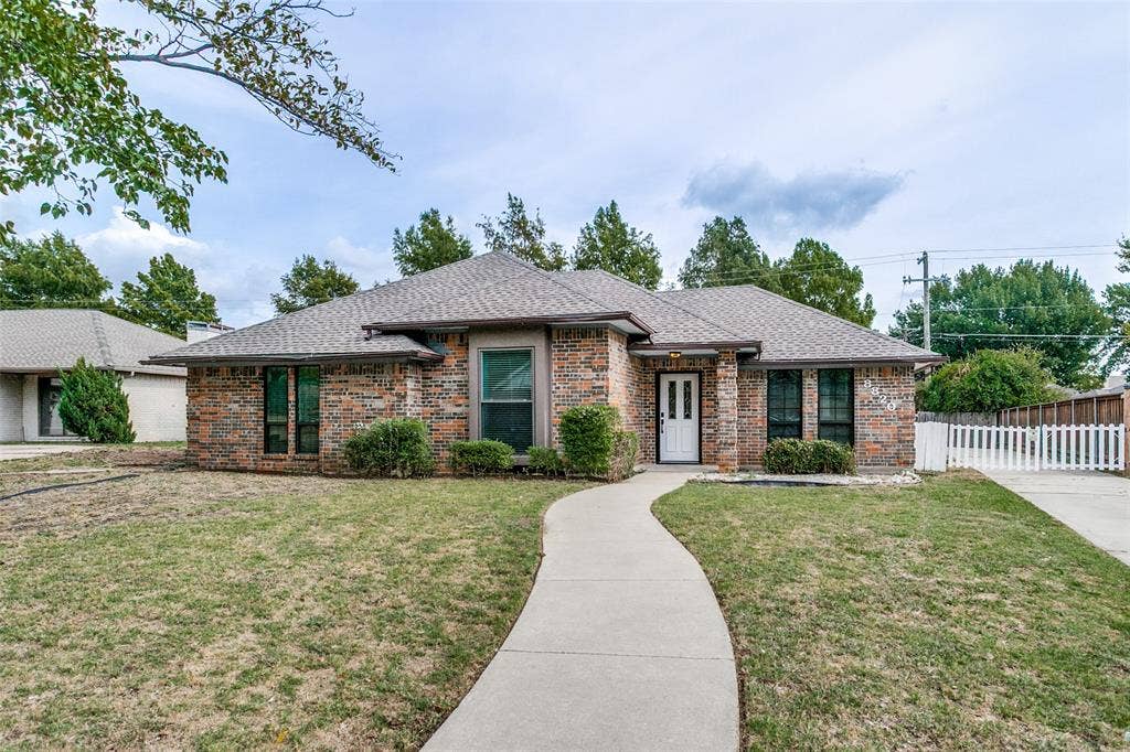 8820 Woodstream Drive, Frisco, TX 75034 Single-story brick exterior featuring a multi-gabled roofline, concrete walkway, and white-paneled entry door with sidelights