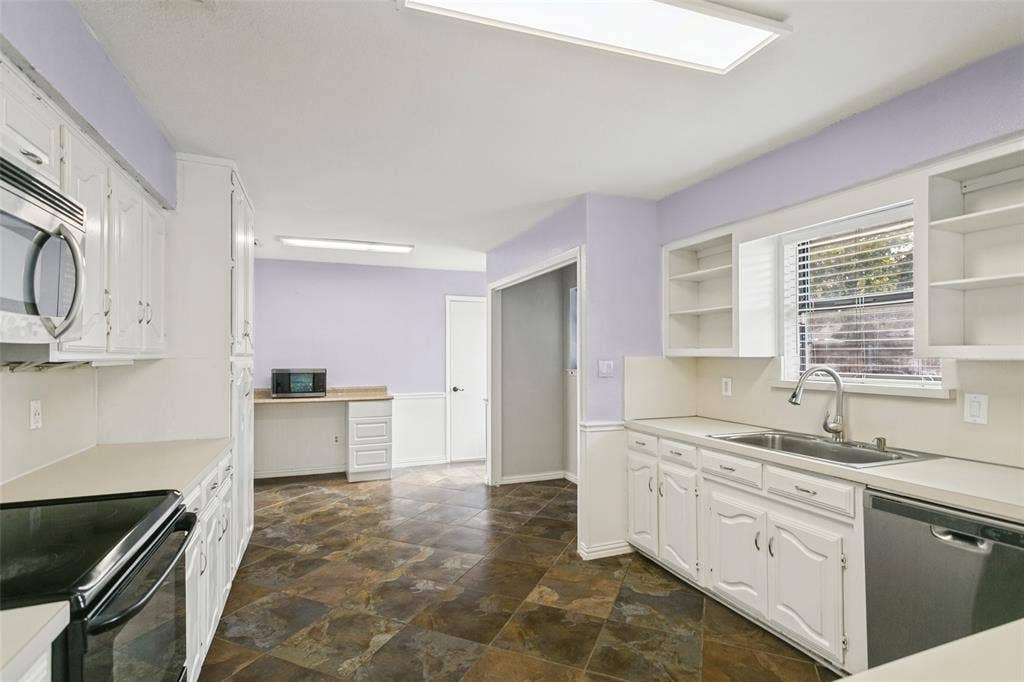 8820 Woodstream Drive, Frisco, TX 75034 Kitchen featuring white cabinetry, solid-surface countertops, stone-finish tile flooring, built-in shelving, and a stainless steel kitchen faucet