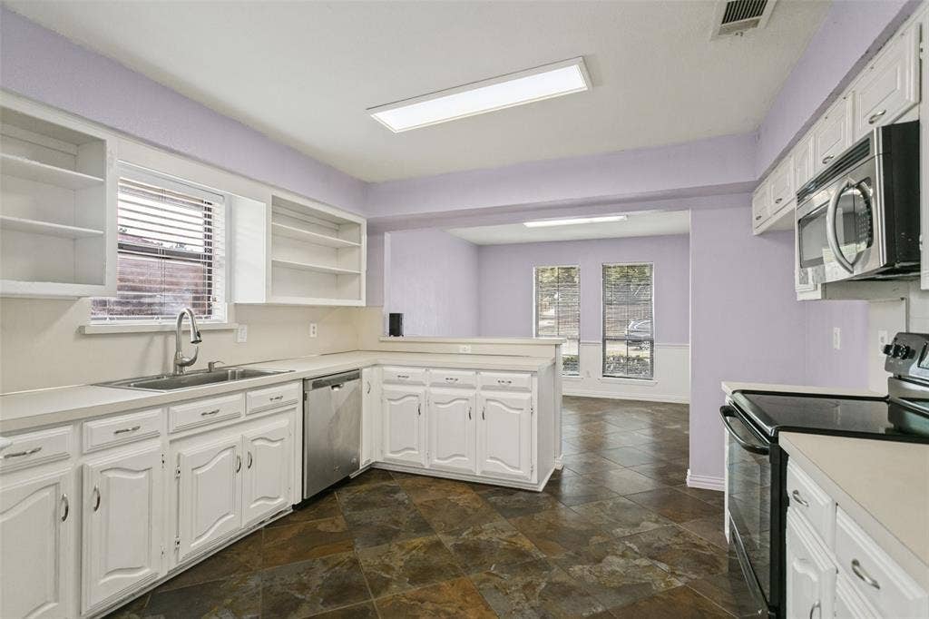 8820 Woodstream Drive, Frisco, TX 75034 Kitchen featuring white cabinetry with raised-panel doors, solid surface countertops, stainless steel dishwasher, integrated microwave, and tile flooring
