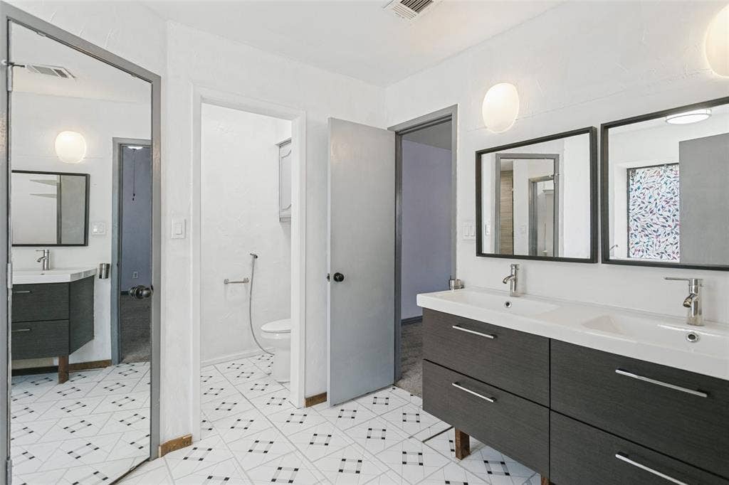 8820 Woodstream Drive, Frisco, TX 75034 Dual-sink vanity with dark wood-finish cabinetry, rectangular vessel sinks, matte metallic faucets, and matching framed mirrors