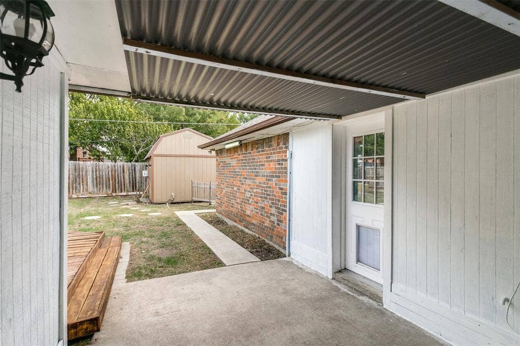 8820 Woodstream Drive, Frisco, TX 75034 Covered patio with corrugated metal roofing, wood-finish exterior siding, brick masonry, and a concrete patio floor