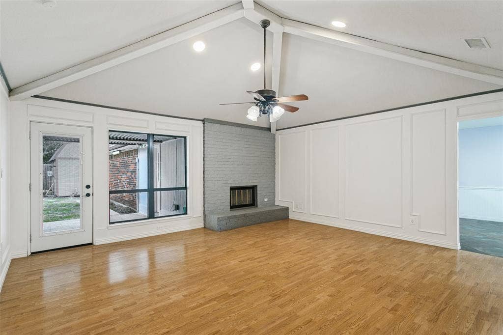 8820 Woodstream Drive, Frisco, TX 75034 Vaulted ceiling with exposed beams, wood-finish flooring, painted brick fireplace with raised hearth, wainscoting wall paneling, and recessed lighting