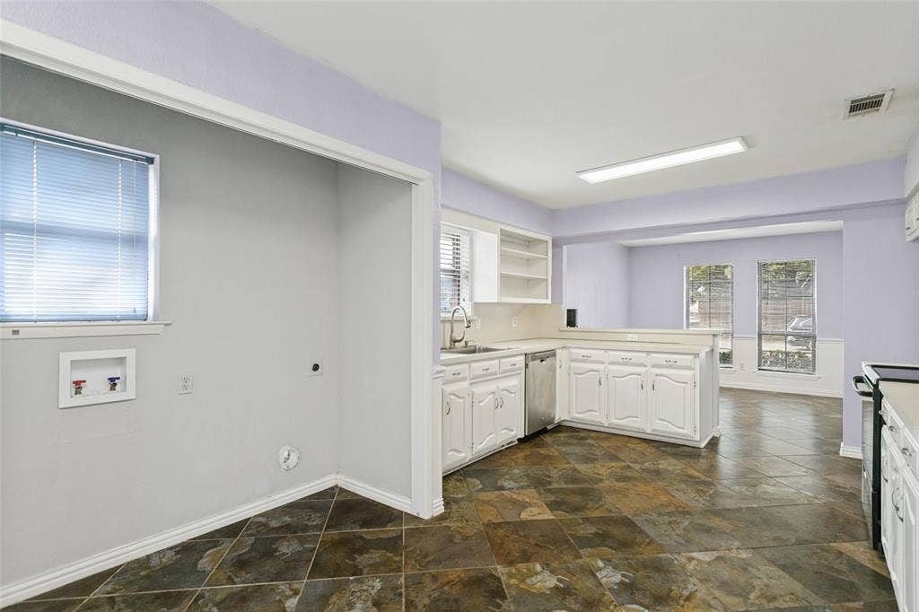 8820 Woodstream Drive, Frisco, TX 75034 Kitchen featuring white cabinetry, integrated dishwasher, stainless steel sink with pull-down faucet, stone-tile flooring, and dedicated laundry hookups