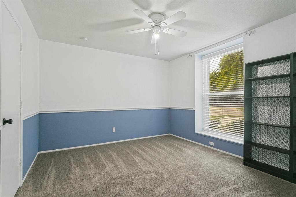 8820 Woodstream Drive, Frisco, TX 75034 Neutral-toned carpeting, two-toned wall paint with chair rail molding, ceiling fan with light kit, and a large window with horizontal blinds