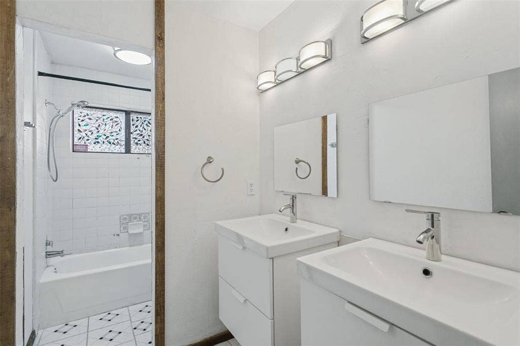 8820 Woodstream Drive, Frisco, TX 75034 Double vanity featuring wall-mounted square mirrors and integrated rectangular sinks, complemented by contemporary polished chrome hardware, multi-light vanity fixtures, and a tiled shower-tub combination