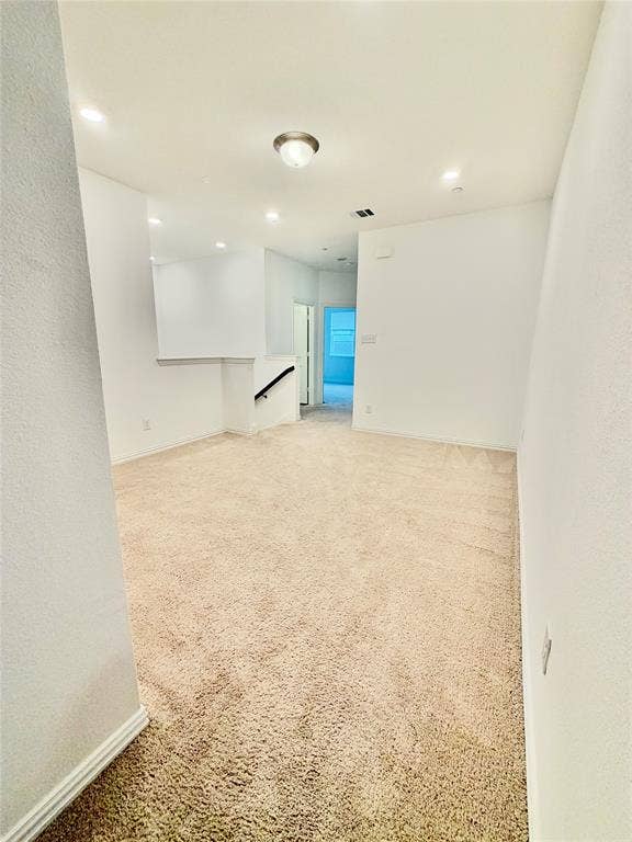 Neutral-toned carpeting, recessed ceiling lighting, a flush-mount light fixture, and a stairwell with a fixed handrail